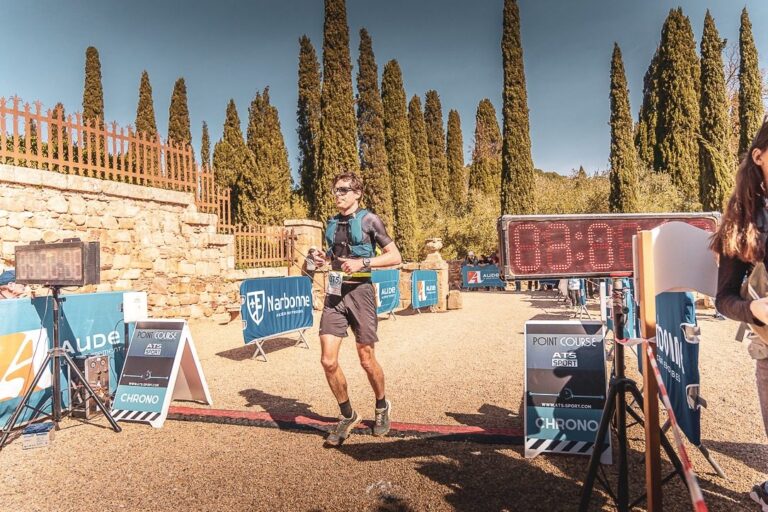 Coureur franchissant la ligne d'arrivée sur les tapis de chronométrage ATS-Sport, horloge digitale affichant le temps de course
